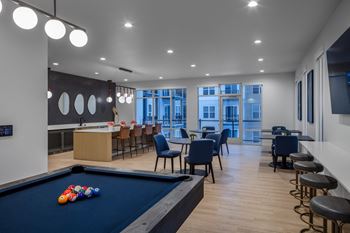 A communal area with a pool table and tables and chairs and a bar